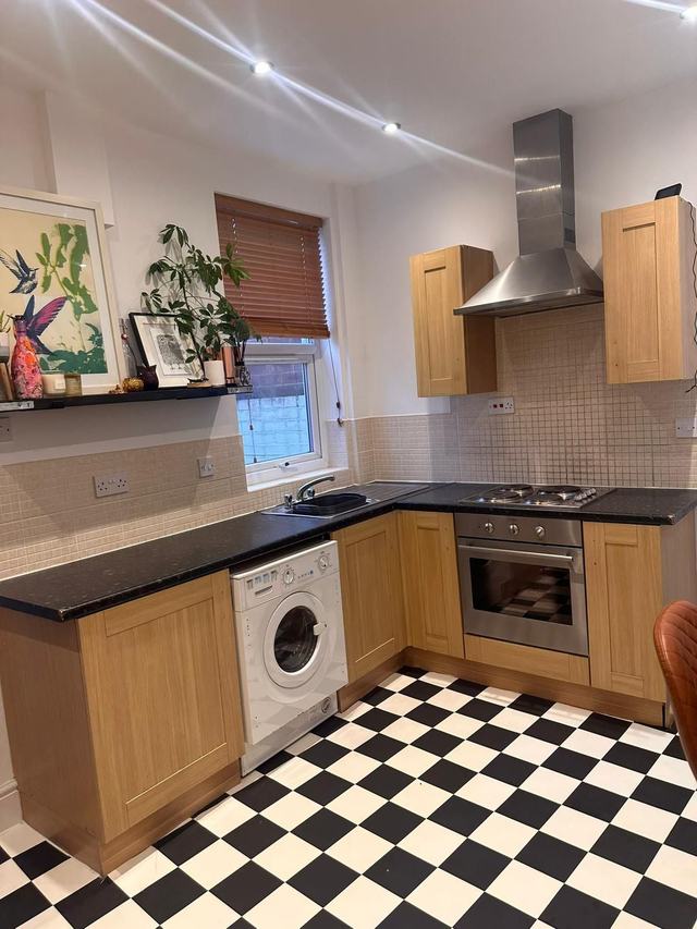 Kitchen with pine-effect doors and a checked floor, before