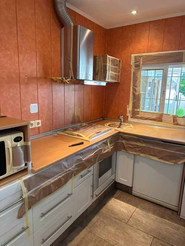 Kitchen with wood-effect units and wall cladding, before